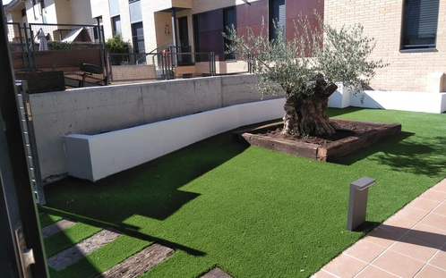 Jardinera de madera alrededor de un árbol junto al césped