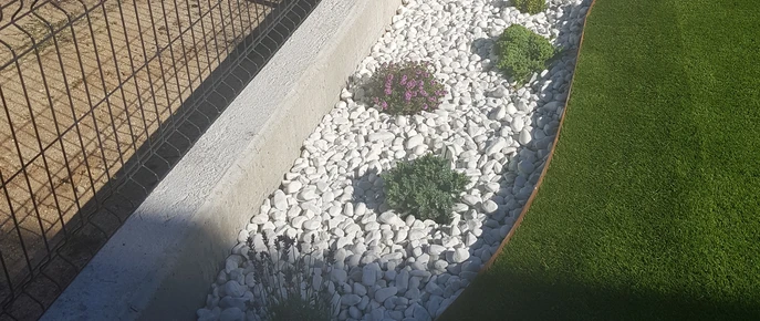 Perfil de acero junto a un parterre de grava blanca y césped