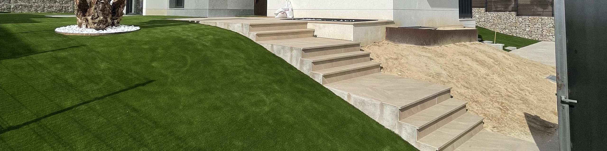 Césped artificial junto a unas escaleras de acceso a una vivienda