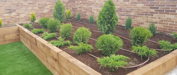 Jardinera de madera con arbustos junto a una pared de ladrillo