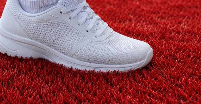 Zapatilla blanca sobre una superficie de césped artificial rojo