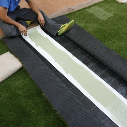 Instalador preparando la banda de unión entre dos piezas de césped artificial