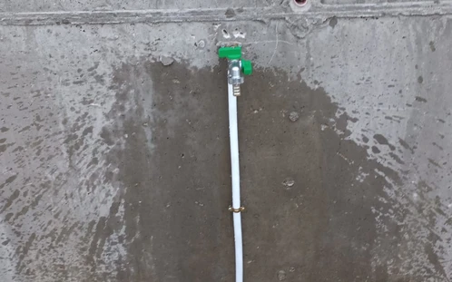 Toma de agua en una pared de obra junto al césped