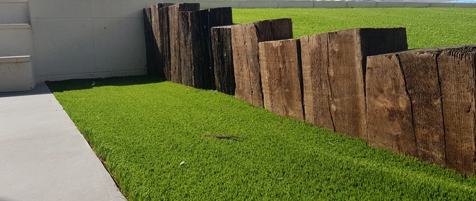 Traviesas verticales de madera junto al césped artificial