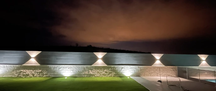 Luces exteriores en un muro al anochecer