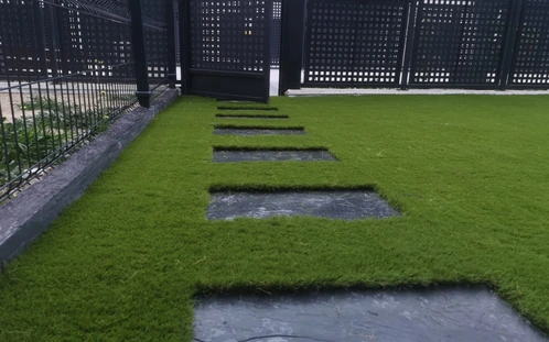 Pasos de pizarra junto a un parterre y una valla