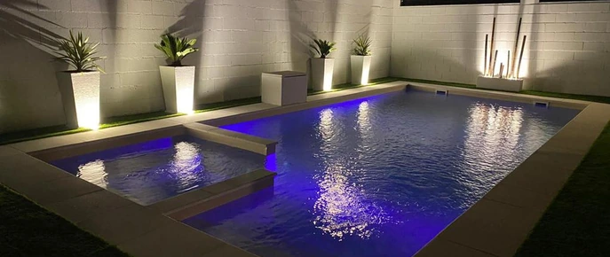 Piscina y jardín iluminados por la noche