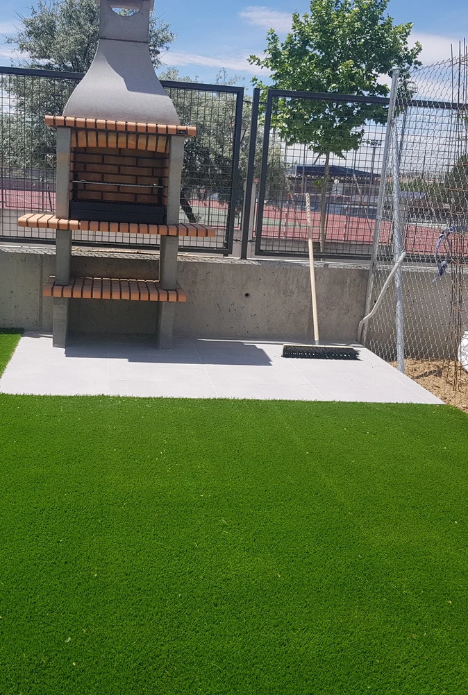 Jardín con césped artificial junto a una terraza pavimentada