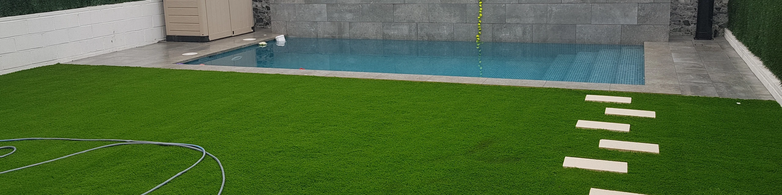 Jardín con piscina, césped artificial y pavimento exterior
