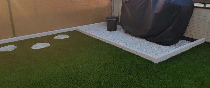 Bordillo blanco delimitando césped y grava en una terraza
