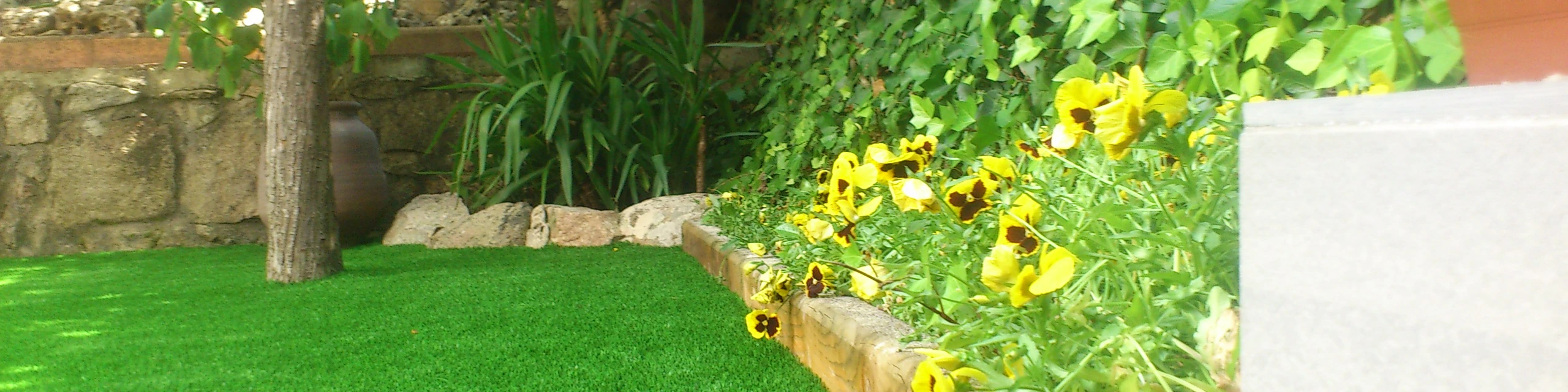 Traviesas de madera delimitando una zona con plantas y césped