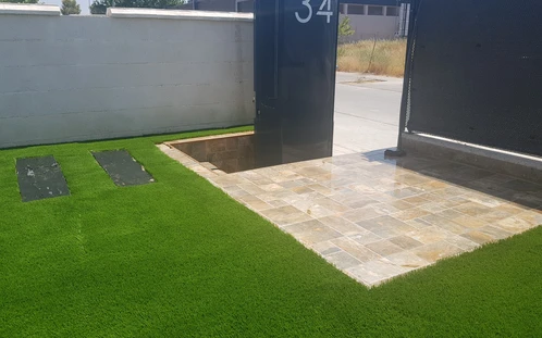 Encuentro de césped artificial con una entrada pavimentada