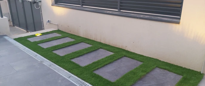 Losetas rectangulares separadas sobre césped junto a una vivienda